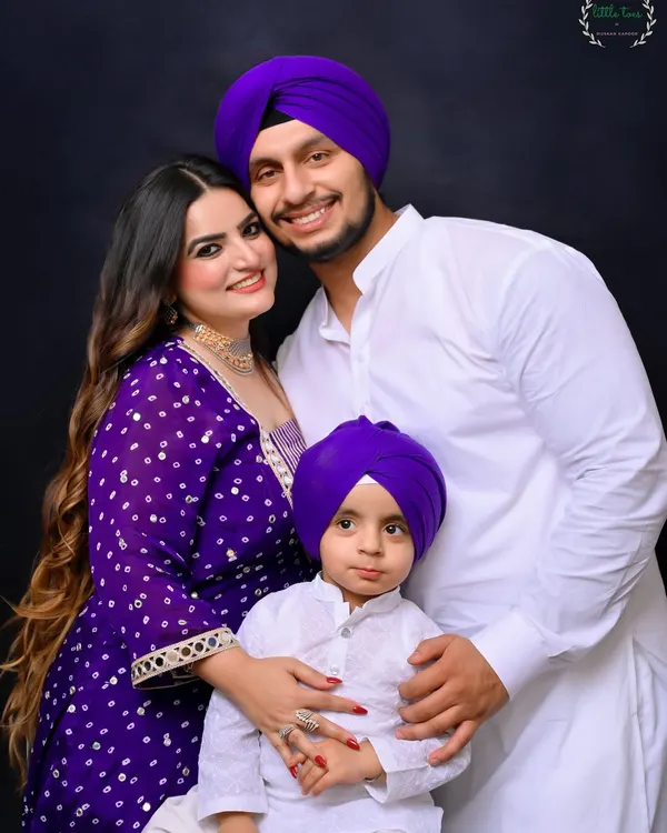 A beautiful studio portrait of a Sikh family, dressed in coordinated white and purple traditional attire. The image radiates warmth and togetherness, showcasing a classic family photograph.