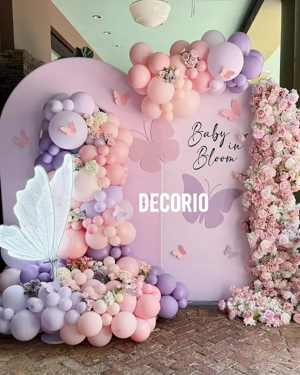 This "Baby in Bloom" butterfly theme is one of my most requested designs for baby showers. I use a custom-arched backdrop, a lush organic balloon garland in pastel pinks and purples, and delicate butterfly accents to create a truly magical photo corner.