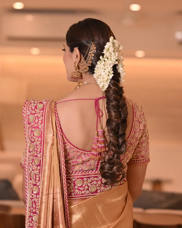 A stunning example of a traditional South Indian bridal braid. This fishtail braid is adorned with fresh jasmine flowers and gold accessories, creating a timeless and elegant look.