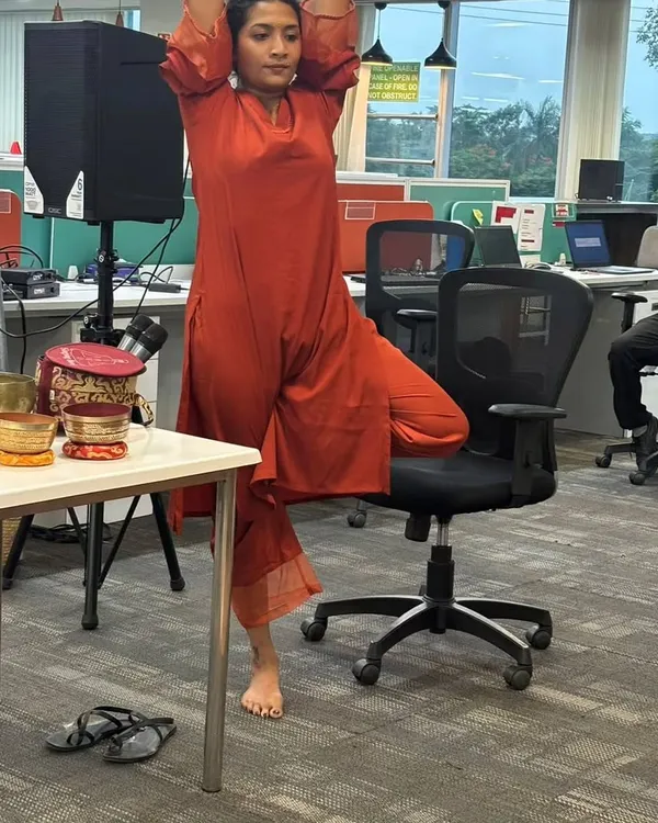 Here I am at MagicBricks demonstrating a modified Tree Pose using an office chair for support. This shows how we can adapt classic yoga postures for the workplace to improve balance and focus without needing a mat.
