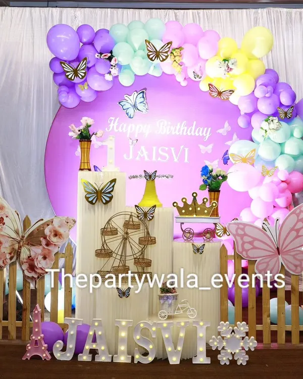 A stunning butterfly-themed party with a pastel rainbow balloon arch and large, colorful butterfly cutouts.