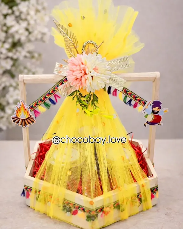 This bright yellow Lohri hamper is designed to capture the festive spirit. Wrapped in vibrant net and decorated with traditional motifs, it's filled with festive favorites and is perfect for family, friends, or corporate gifting.