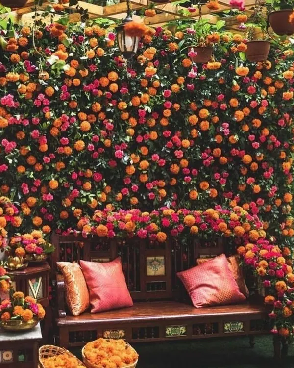 A stunning Haldi backdrop made entirely of a dense wall of orange and pink marigolds. This is a classic choice that always looks incredible in photos.