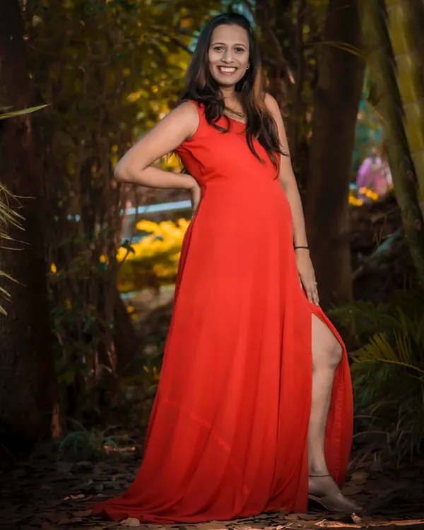 A stunning solo portrait in a vibrant red gown. The thigh-high slit adds a touch of glamour, perfect for a mom-to-be who wants to feel confident and beautiful.