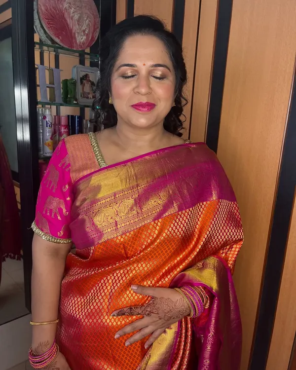 A close-up of Dipti's makeup. The gold shimmer on the eyes and the bright pink lip create a festive and joyful look.