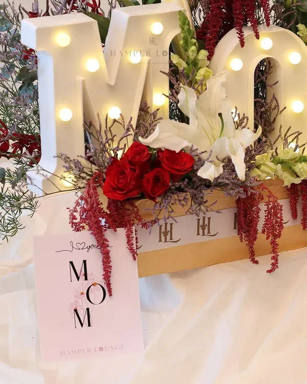 This Mother’s Day, I designed the "MOM" hamper to be the heart of the celebration. The light-up letters are surrounded by a lush arrangement of red roses, white lilies, and other exotic florals, creating a truly show-stopping gift.