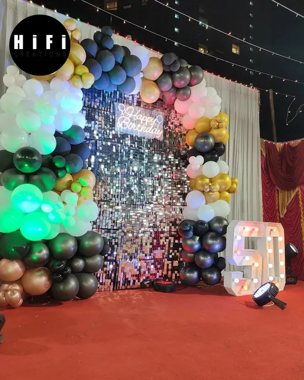 A glamorous 50th birthday celebration with a black, gold, and white theme. The decor features a stunning sequin wall and a large light-up number '50'.