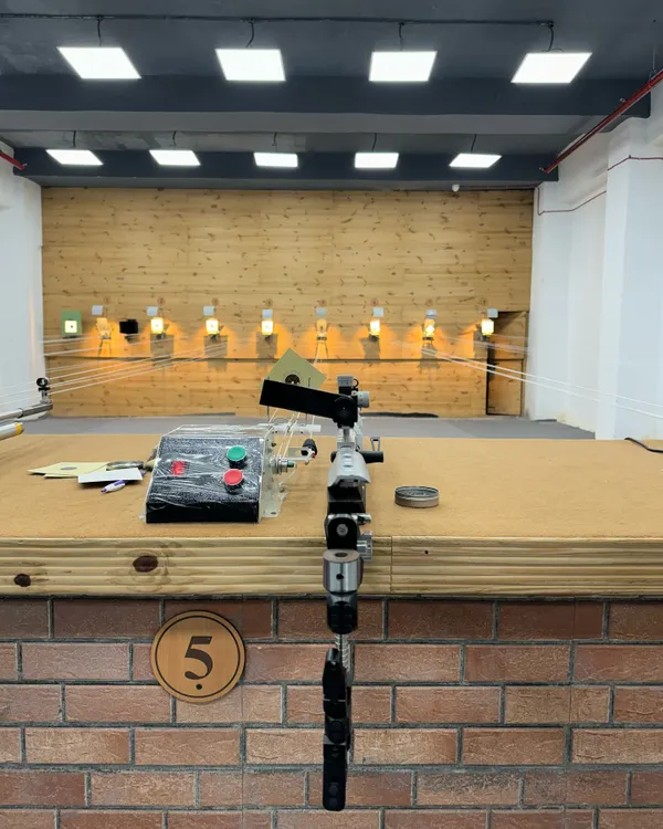 Your lane is ready. This is a shooter's view of our professional setup, featuring an air pistol and the electronic target system you will train with from day one.