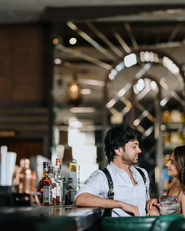 A stylish pre-wedding shoot in a sophisticated bar. The couple shares a conversation at the counter, creating a candid and modern urban love story.