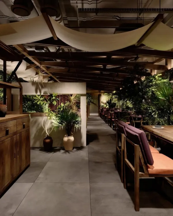 A work-in-progress render of a restaurant with a rustic, biophilic design. The visualization explores the interplay of raw wood, concrete, and abundant greenery.