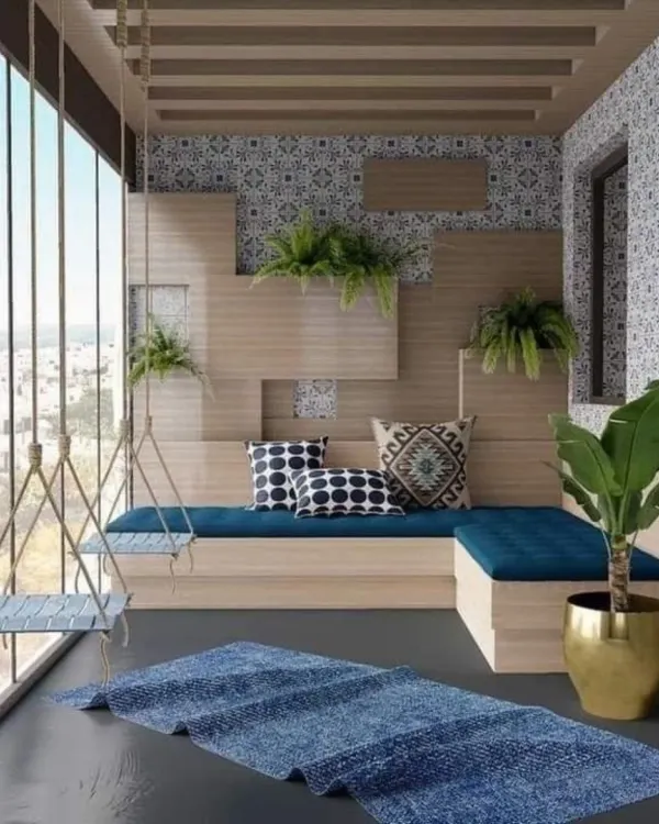 This unique enclosed balcony features two hanging swing seats and a built-in bench, all with bold blue cushions. The design is defined by patterned wall tiles and a creative wooden wall structure that doubles as a planter.