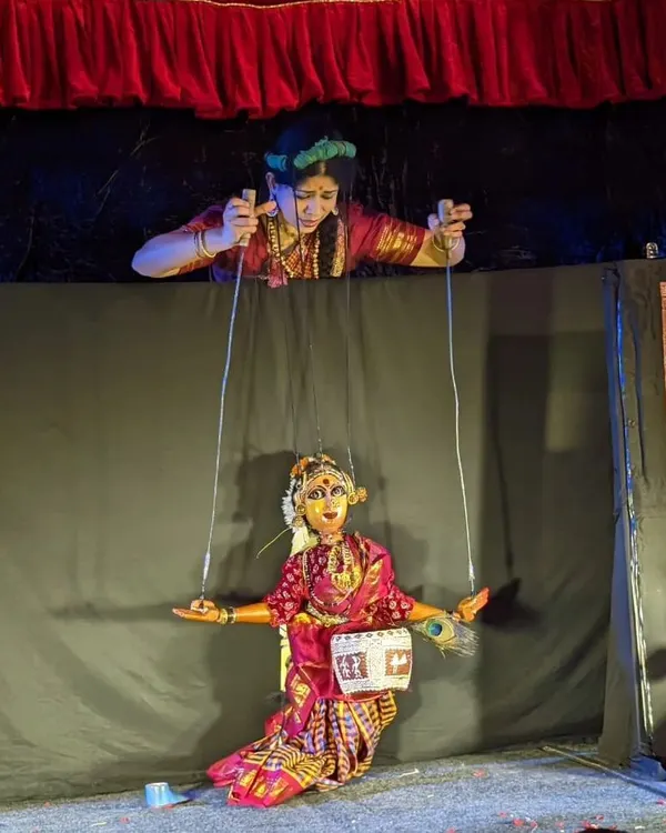 A puppeteer skillfully manipulates a string puppet from above the stage. This view shows the technique and focus required to make the puppet dance and express emotion, bringing the character to life for the audience below.