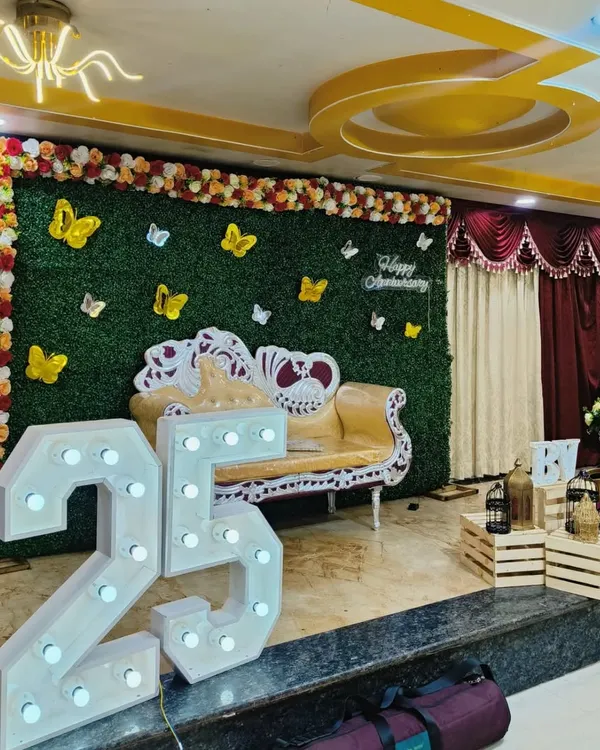 This is another view of the 25th-anniversary stage, showing how the elements come together in a larger venue. The combination of the green wall, floral arrangements, and prominent light-up numbers creates a complete and festive look.