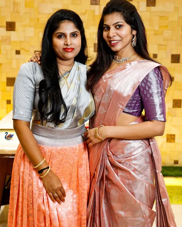 A portrait of two women in elegant sarees at a family event. I enjoy capturing photos of guests enjoying the celebration.