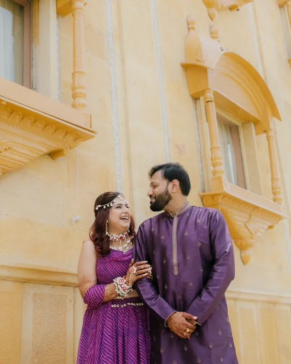 A candid moment between the couple against the beautiful architecture of the Chokhi Dhani Palace Hotel, capturing a natural, happy interaction.