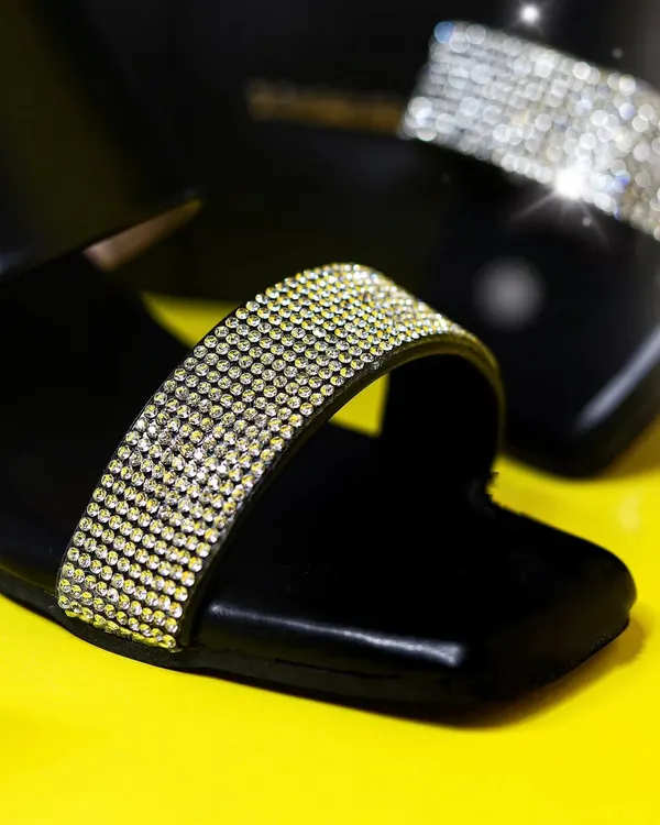 A vibrant close-up of a Dressberry sandal, focusing on the sparkling strap against a bright yellow background for a bold, commercial look.