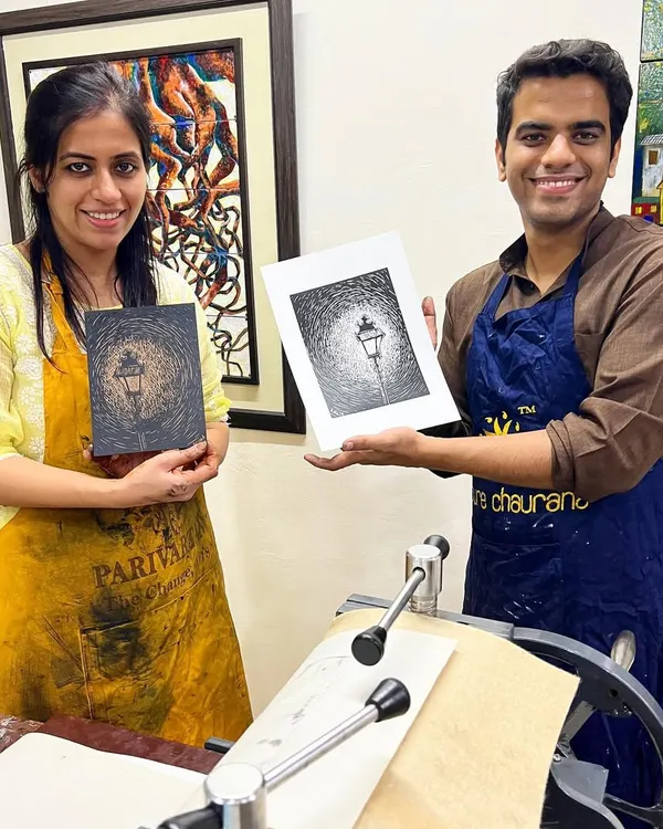 A student proudly displays their finished linocut print next to the carved block. Our workshops are led by expert printmakers like Tarun Sharma.