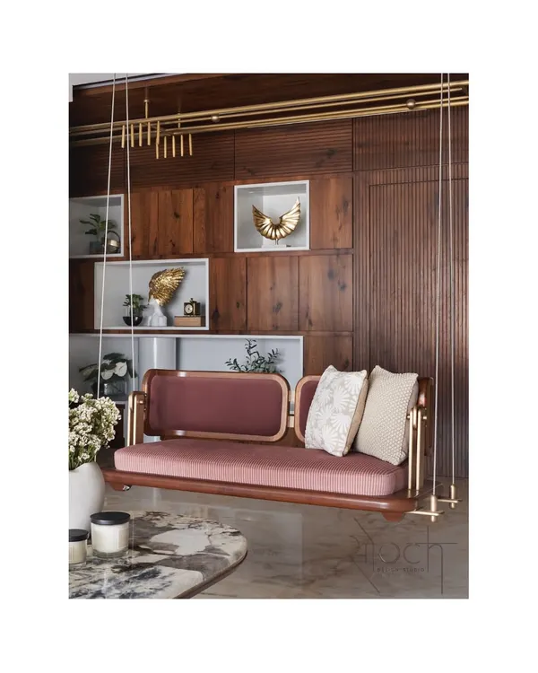 This reversible teakwood swing is one of our signature creations, a perfect blend of playful functionality and elegant design. Crafted with a solid wooden base, mauve textured upholstery, and finished with matt gold brass fixtures, it serves as a stunning centerpiece in any luxury living room.