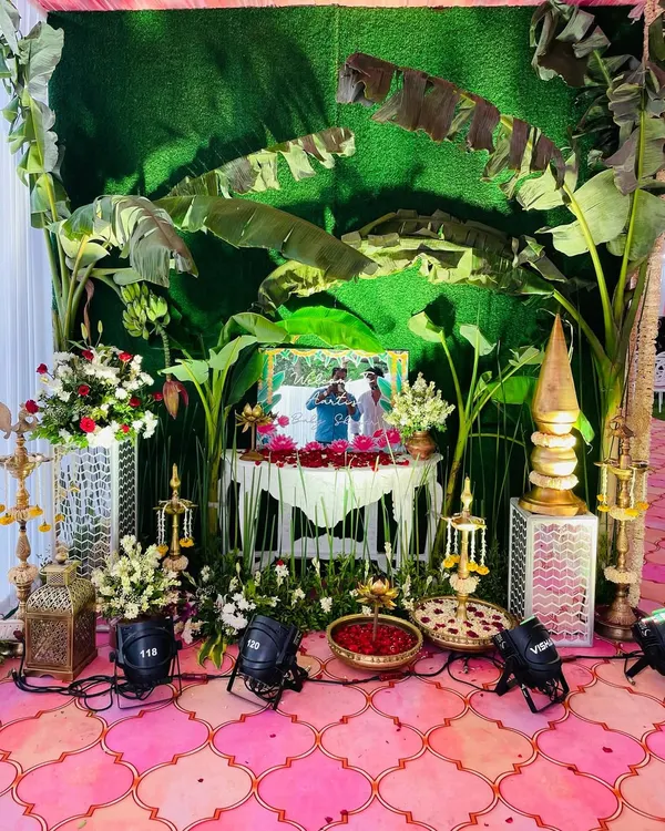 A traditional baby shower setup with a backdrop of lush banana leaves. The decor includes authentic elements like brass lamps and floral arrangements, creating a classic South Indian vibe.