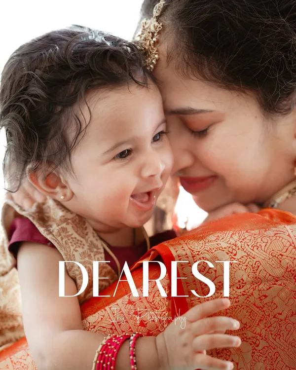 A beautiful, candid moment showing the pure joy and connection between a mother and her laughing baby during a naming ceremony. This close-up highlights the baby's happy expression and the mother's loving gaze.