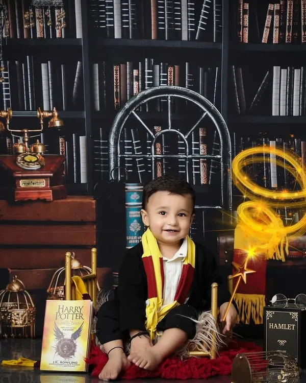This little wizard is sitting proudly in his magical library. The detailed Harry Potter themed setup includes iconic books, a Hedwig prop, and warm lighting to create an authentic and enchanting scene for a first birthday photoshoot.