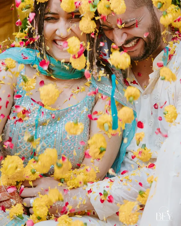 The moment of impact. A couple shares a laugh as they are showered with marigold and rose petals during their vibrant Haldi ceremony in Chandigarh.