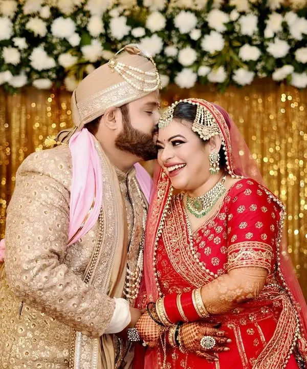 A perfect candid moment of pure happiness. The groom's affectionate kiss and the bride's joyful laugh are what candid wedding photography is all about.