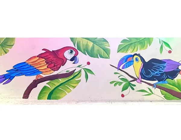 This completed mural shows a macaw and a toucan perched among tropical leaves. I use durable acrylics to make sure the art stays bright, even outdoors.