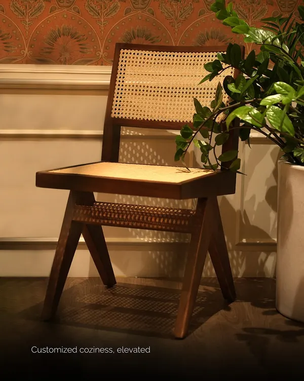 This chair is a modern interpretation of a classic design, featuring a solid teak wood frame with natural cane woven into the seat and back for customized coziness.