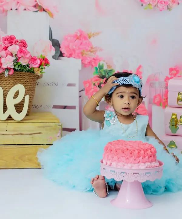 A princess and her cake! This little girl looks a bit unsure about the pink cake in front of her, making for a cute and funny moment during her first birthday cake smash photoshoot.