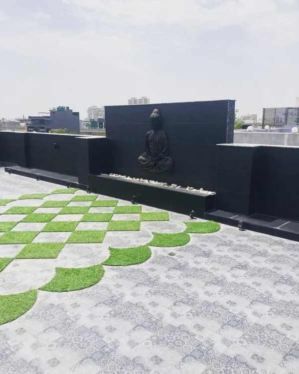 This is a wider view of the serene terrace project, showing how the Buddha water feature, checkerboard flooring, and low boundary walls come together to create a spacious and peaceful rooftop environment.