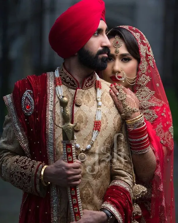 For a truly royal wedding look, we offer coordinated sets like this one. The bride is in a classic red lehenga with intricate gold embroidery, perfectly matched with the groom's beige and gold brocade sherwani and a striking red turban. This is a perfect example of our Punjabi and Sikh wedding attire rental collection.