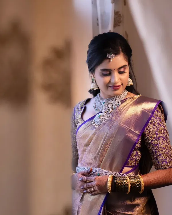 A soft and elegant reception look. This bride is wearing a beautiful purple and gold saree, and her makeup is subtle yet glamorous, with shimmery eyeshadow and diamond jewellery.