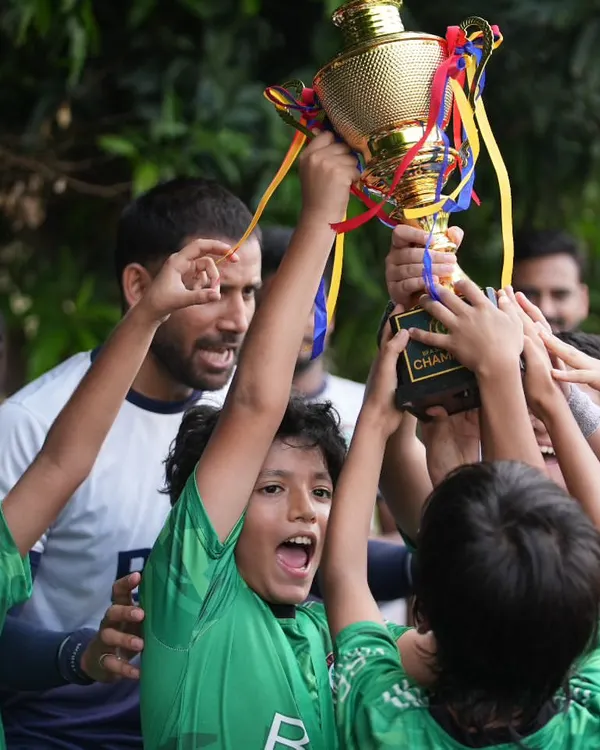 The roar of champions. This moment captures the pure elation of our young team as they lift the trophy, a testament to their collective effort.