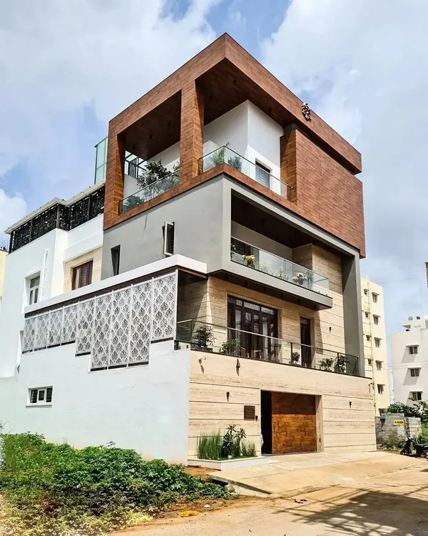 This contemporary villa elevation showcases our integrated approach to architecture and design. The structure features a striking combination of wood cladding, stone, and glass, creating a bold and modern facade with multiple balconies and a rooftop terrace for a complete indoor-outdoor living experience.