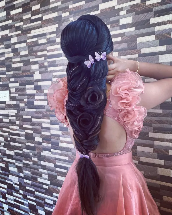 An advanced, sculptural braid featuring multiple rose shapes woven into the plait, accented with delicate butterfly clips. This hairstyle is a true demonstration of artistic skill.