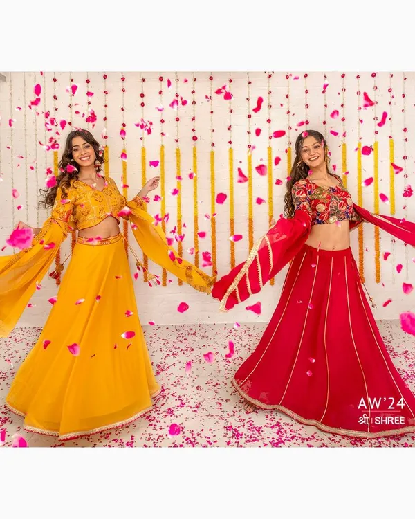 A dynamic shot for the SHREE Autumn Winter '24 collection, capturing the movement and vibrant colors of festive lehengas. The falling petals add a celebratory feel, perfect for a seasonal campaign.