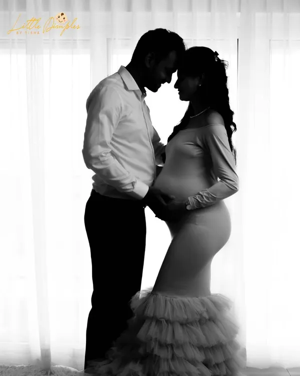 A stunning black and white silhouette of an expecting couple against a bright window. This technique creates a dramatic, intimate, and timeless maternity portrait.