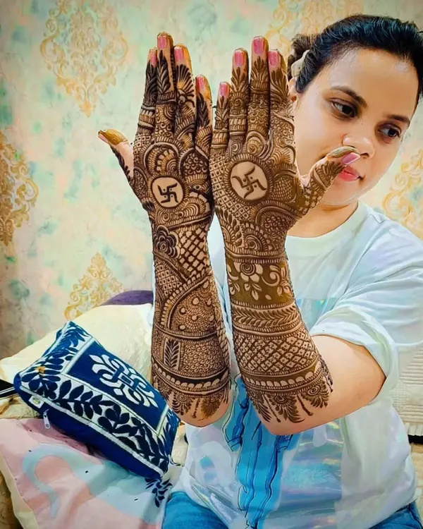 A beautiful Karva Chauth or Diwali mehandi design featuring the auspicious swastika symbol in the center of the palms. The design is full and intricate, perfect for a grand festive celebration.
