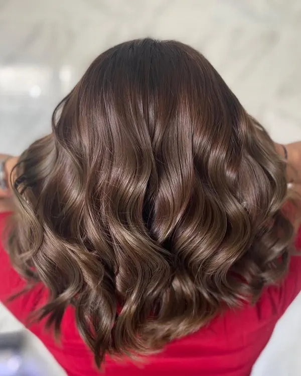 This glossy ash-brown color is one of our absolute favorites to create. We gave it a soft wave to show off the multi-dimensional tones and healthy shine that you can only get with damage-free color. It's giving major glow up!