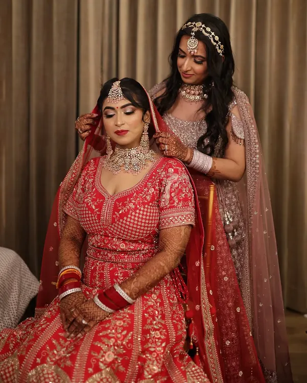 A sweet moment between sisters. The bride's sister helps with the final touches, adjusting the dupatta. It's these moments that make a wedding so special.