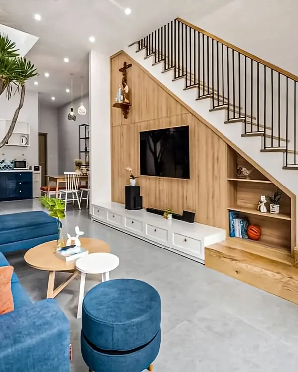 We believe in making every square foot count. This living room demonstrates our approach to integrating stylish entertainment centers into the home's architecture, like this TV unit built under the staircase, creating a functional and visually appealing focal point.