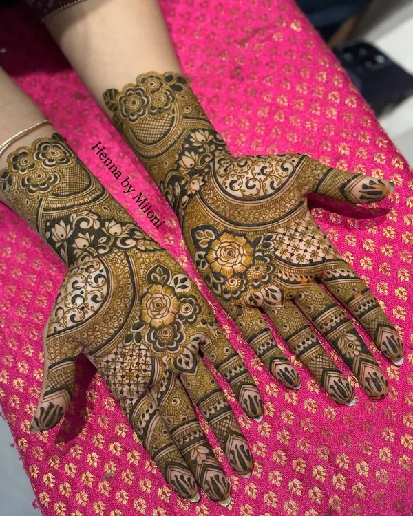 A stunning example of reverse henna technique, where the background is filled to make the floral motifs pop. This creates a bold, dramatic effect that looks amazing in photos.