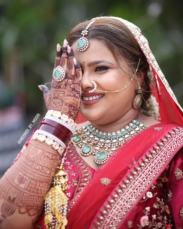 A happy bride showing off her beautiful mehndi stain. The deep reddish brown color of the henna looks stunning against her bridal attire and jewelry. This is the result of good henna and proper aftercare.