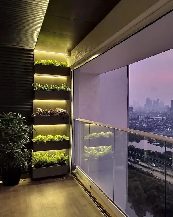 We designed and installed this modern balcony garden in a Mumbai high-rise, featuring custom-built planters with integrated backlighting to create a dramatic evening ambiance. This setup provides a serene city escape with a curated selection of plants suited for urban environments.
