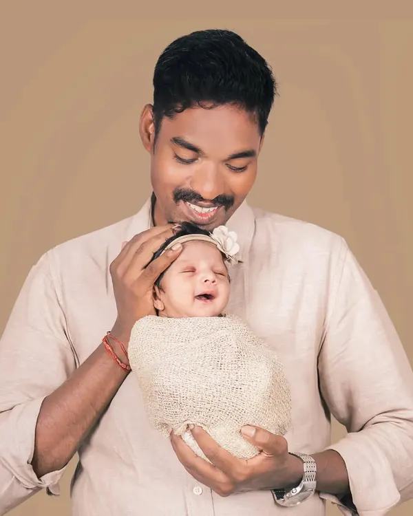 A father's gentle hold and a baby's happy smile. This candid moment between a dad and his daughter is what family portraits are all about.