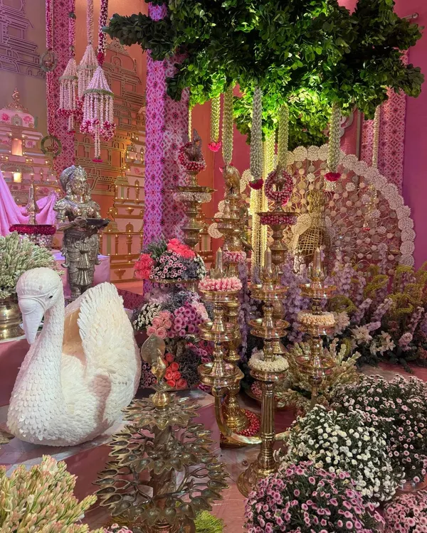 An opulent display for Anant and Radhika’s Raas Garba, where a magnificent swan crafted from flowers sits amongst tiered brass lamps and lush floral arrangements. This setting was part of a larger design celebrating divine love with traditional Indian decor elements.