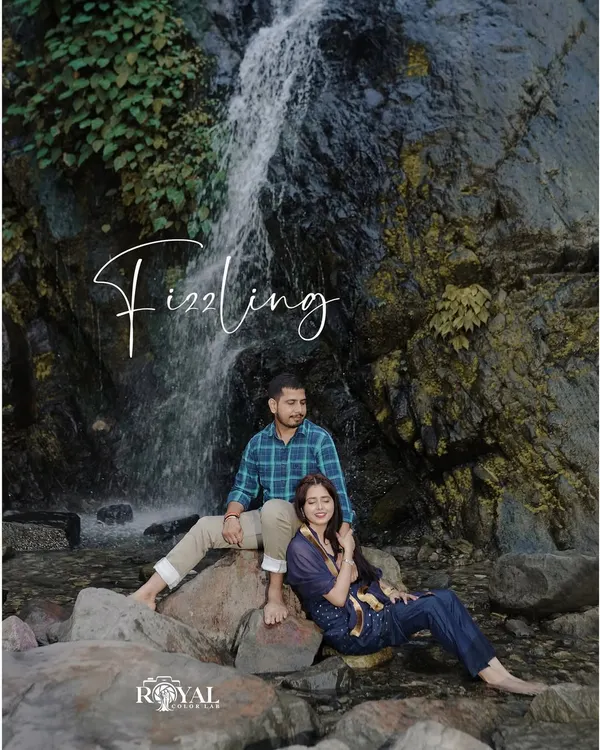 A serene pre-wedding portrait of a couple sitting by a cascading waterfall, perfectly blending romance with the beauty of nature.