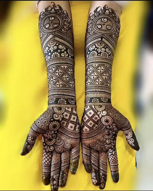 A stunning example of symmetrical, full-coverage mehandi featuring geometric checks, floral bands, and paisleys for a timeless bridal look.