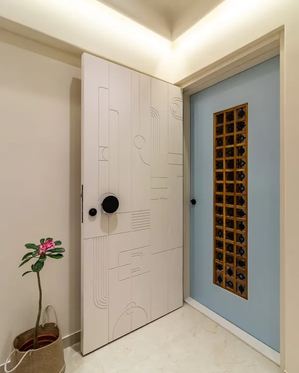 A modern and minimalist main door and safety door combination. The safety door features abstract routed lines, while the inner door has a unique artistic metal grill, creating a layered and intriguing entrance.